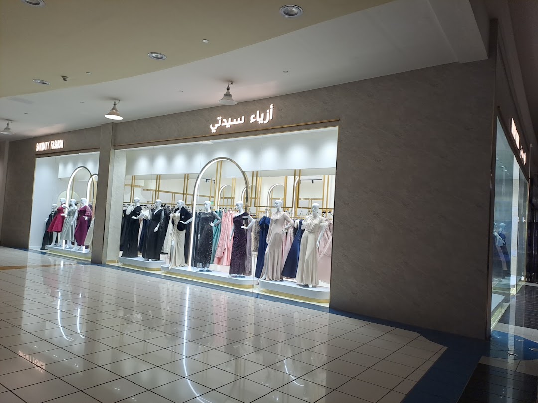 A fashion boutique displays elegant dresses on mannequins in a well-lit mall storefront.